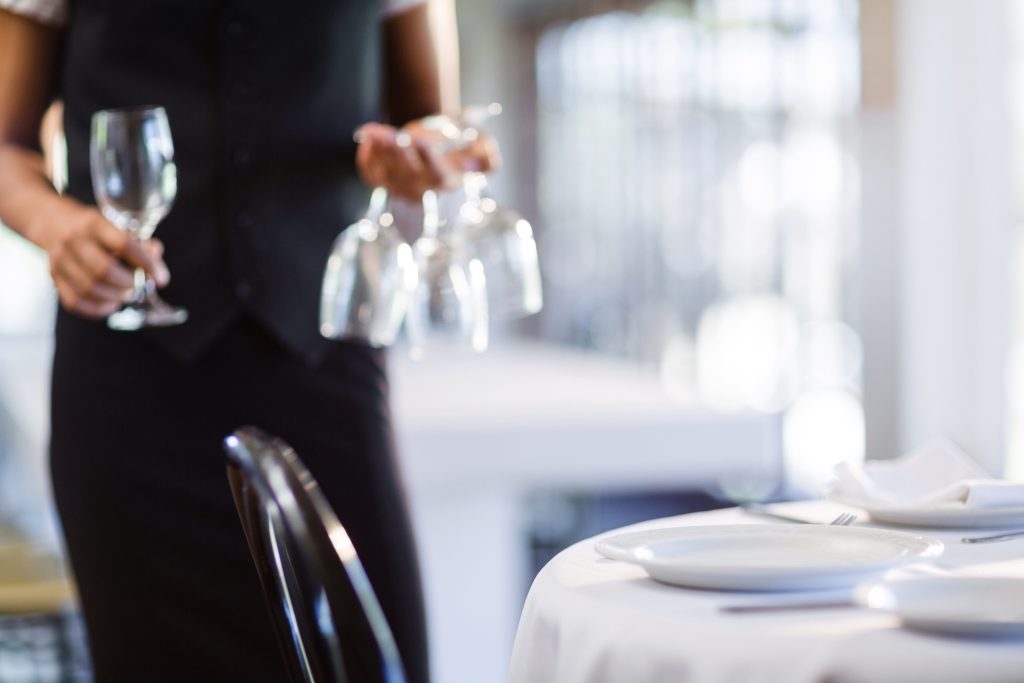 Mid section of waitress setting the table